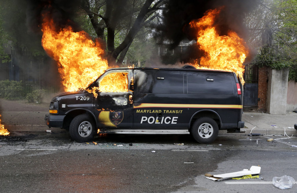 A police vehicle burns, Monday, April 27, 2015, during unrest following the funeral of Freddie Gray in Baltimore. Gray died from spinal injuries about a week after he was arrested and transported in a Baltimore Police Department van. (AP Photo/Patrick Semansky)